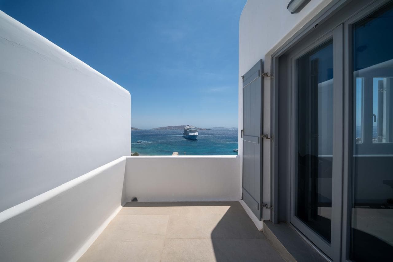 White balcony above the Aegean with a passing ferry