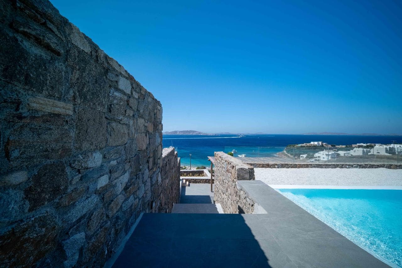Swimming pool framed by stone walls against the Aegean