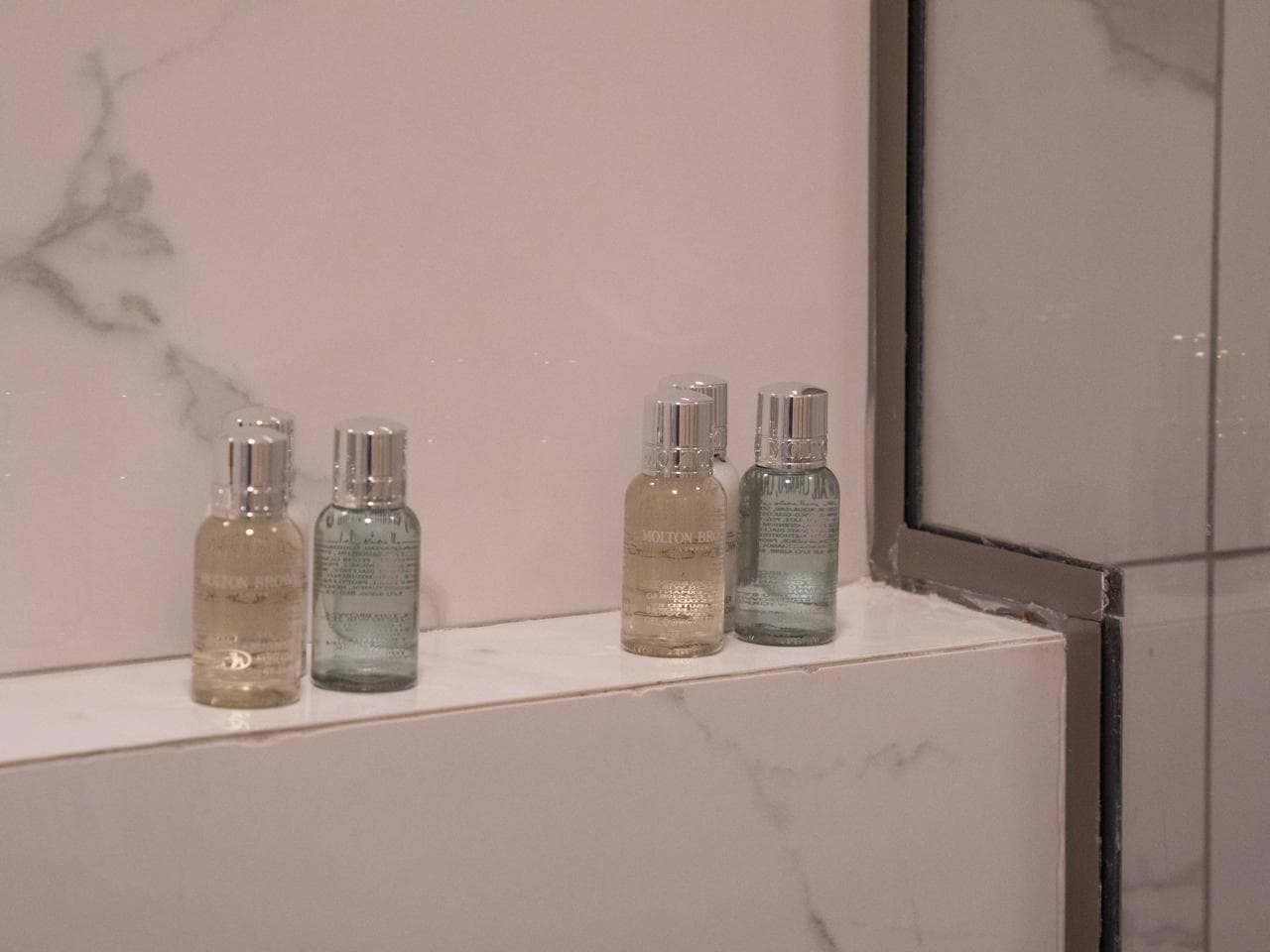 Toiletries lined on the marble shower ledge