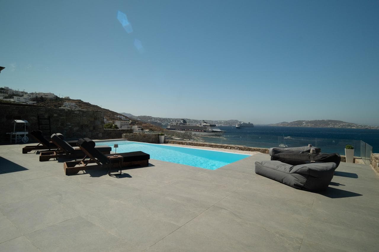 Pool deck with sun loungers facing Mykonos bay
